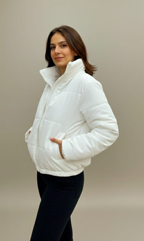 Woman wearing a white puffer jacket against a beige background