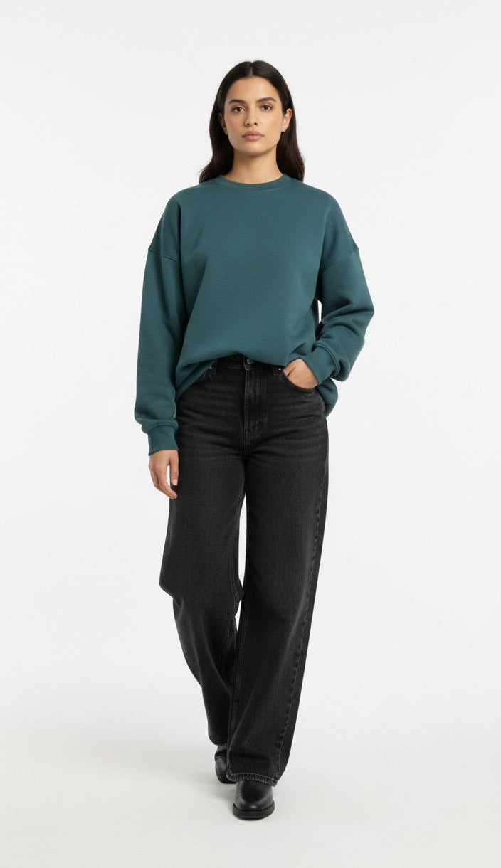 Woman wearing a teal sweater and black pants on a white background
