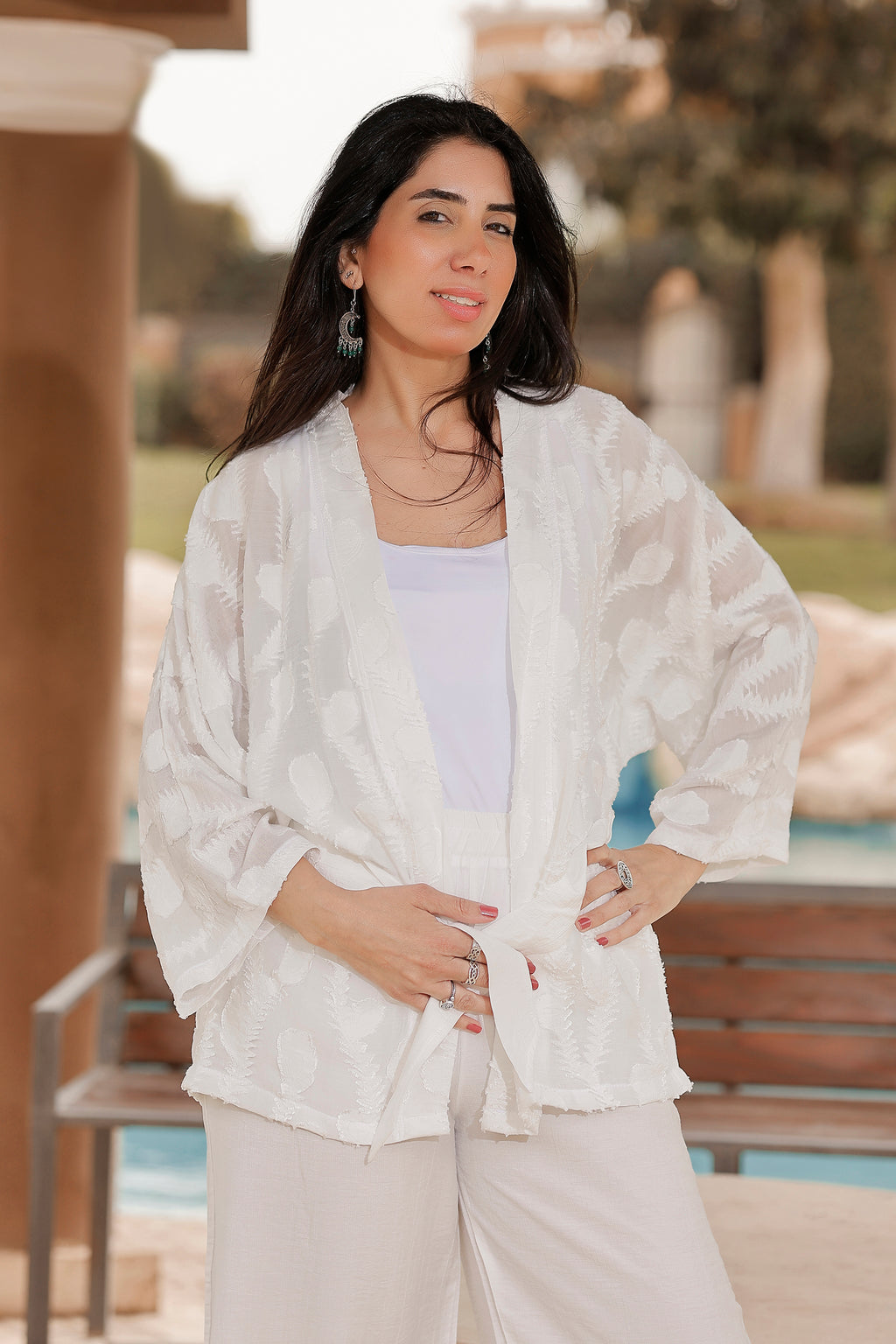 Woman wearing a white lace jacket and pants outdoors
