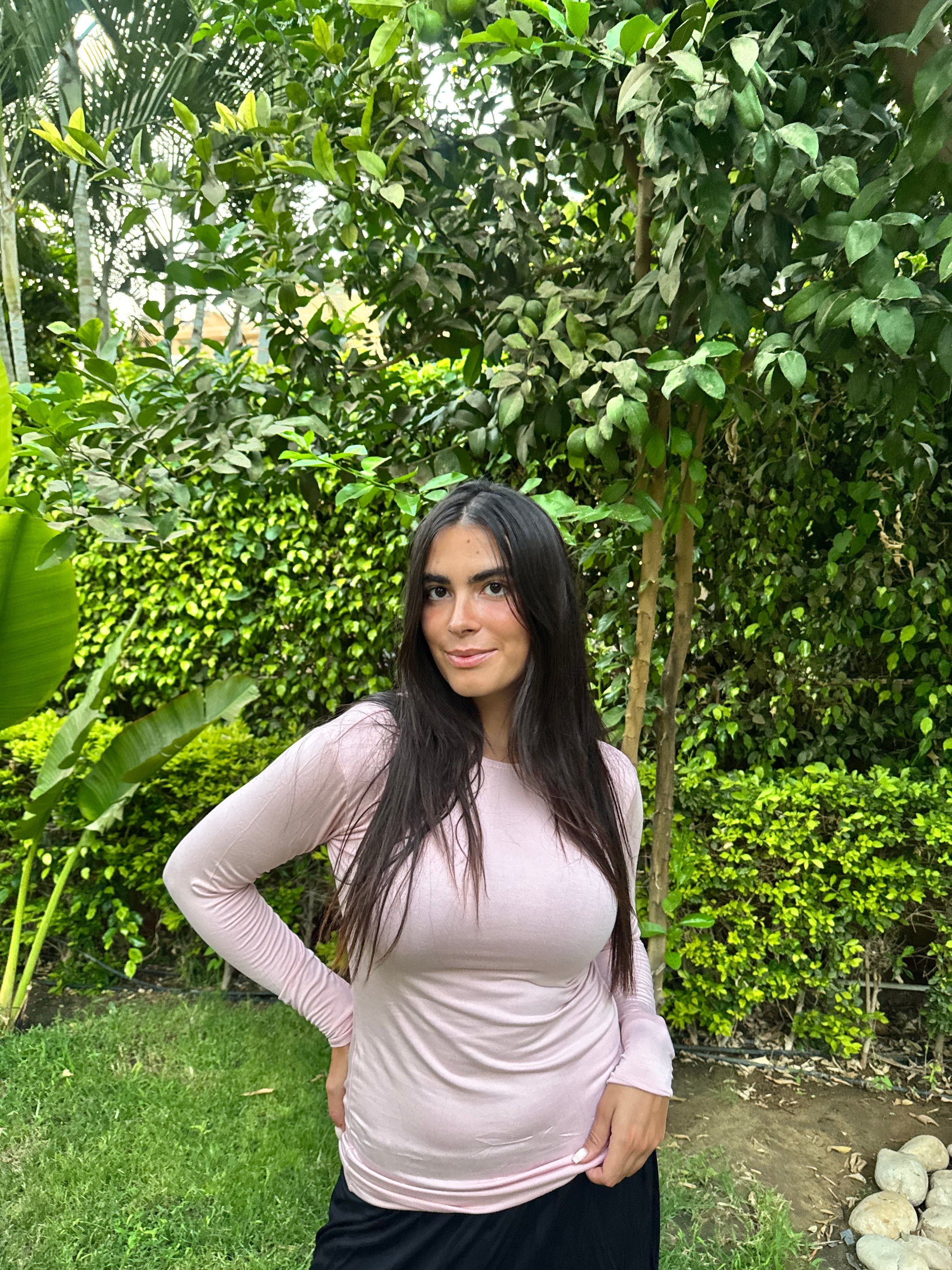 Woman in a pink shirt standing in a lush green garden