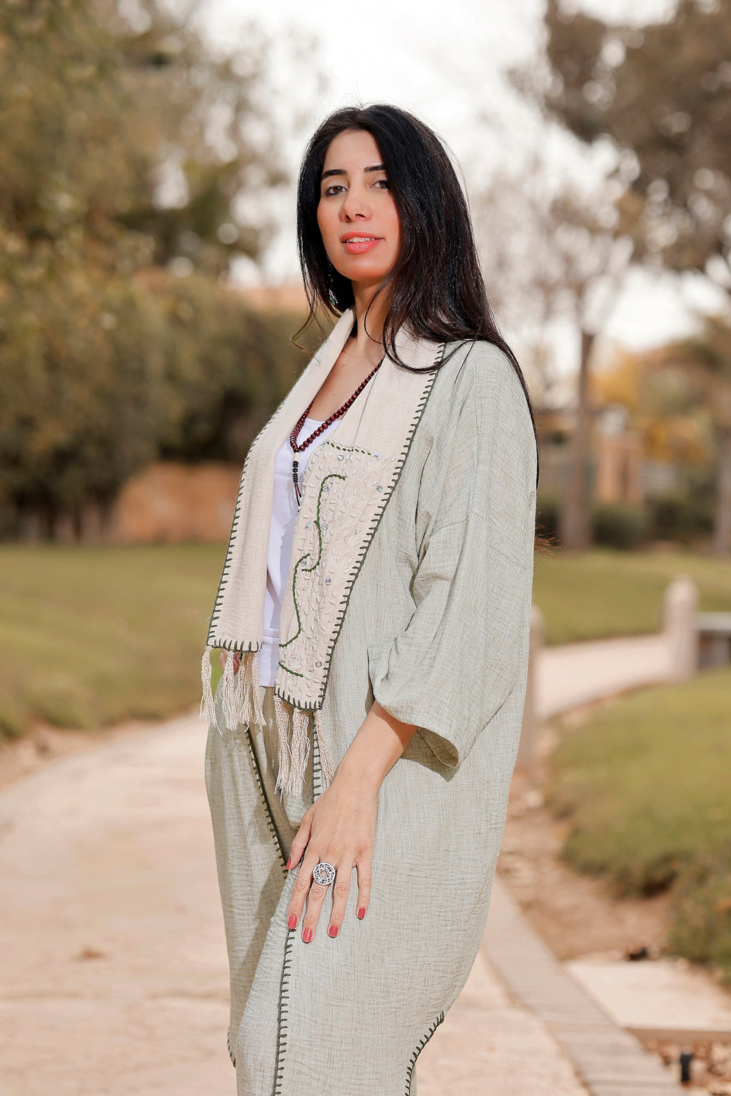 Woman wearing a light-colored outfit with a patterned shawl in an outdoor setting